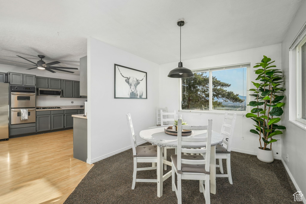 Dining area featuring ceiling fan and light carpet