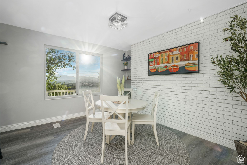 Dining room featuring brick wall and wood finished floors