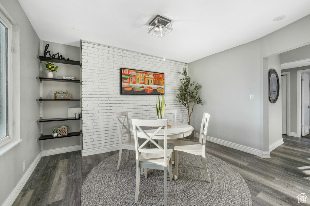 Dining space with wood finished floors and brick wall