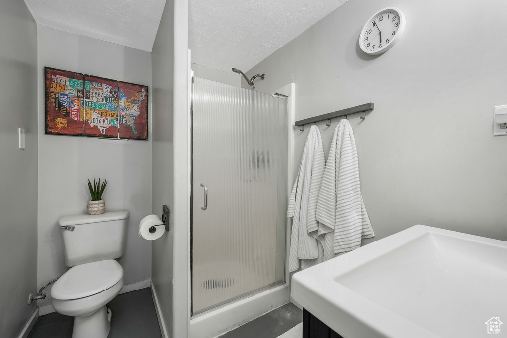 Full bath with a shower stall, a textured ceiling, and vanity