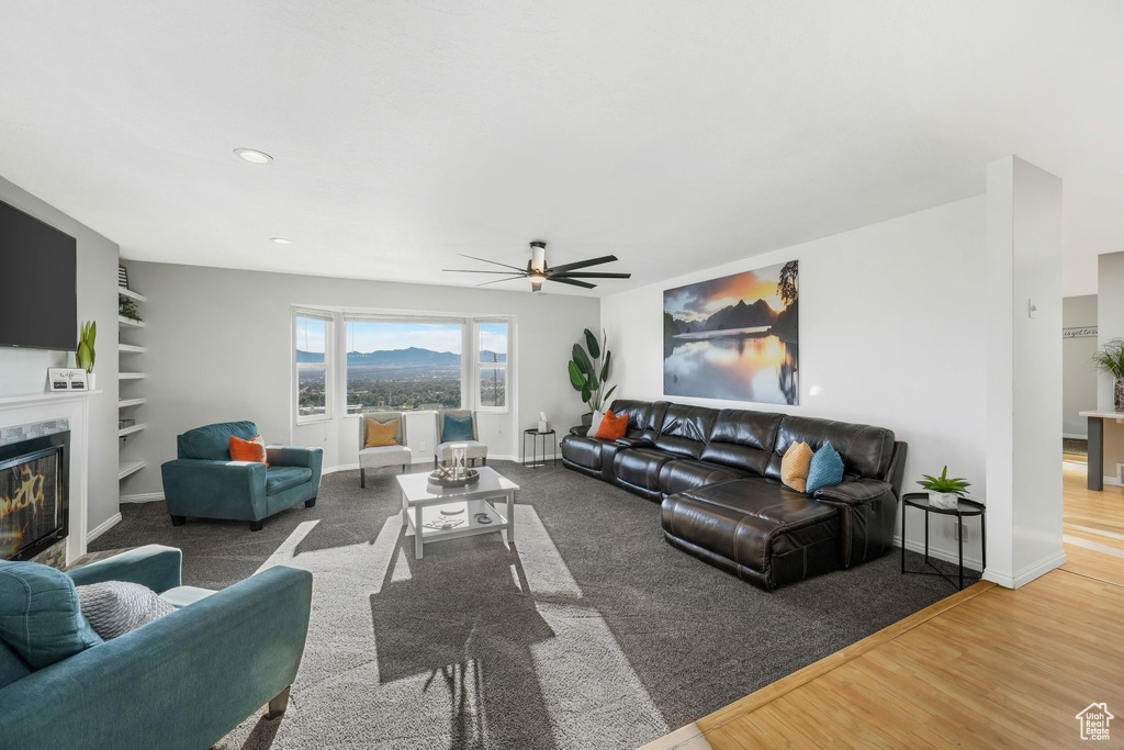 Living area featuring ceiling fan, a fireplace, built in features, and wood finished floors
