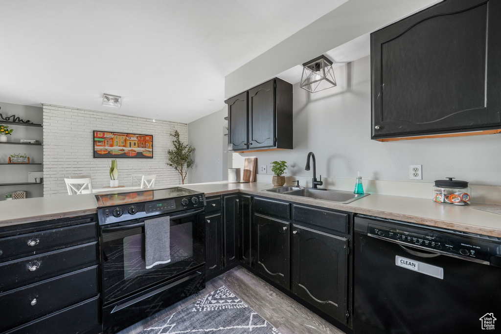 Kitchen featuring black appliances, dark cabinetry, wood finished floors, and light countertops