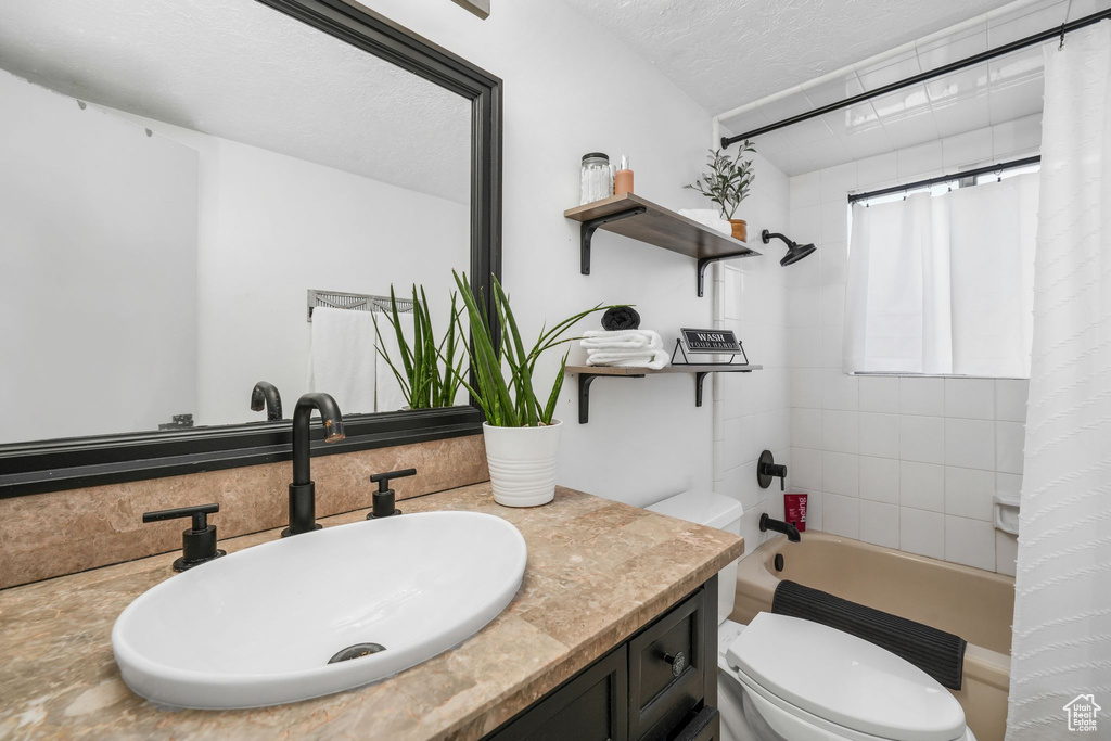 Bathroom featuring vanity, shower / bath combo, and a textured ceiling