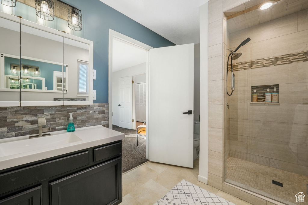 Bathroom featuring a shower stall, vanity, backsplash, and tile patterned floors
