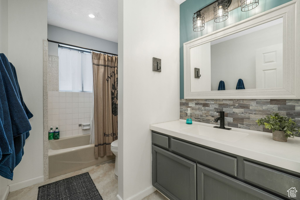 Bathroom featuring vanity, backsplash, shower / bath combination with curtain, and tile patterned flooring