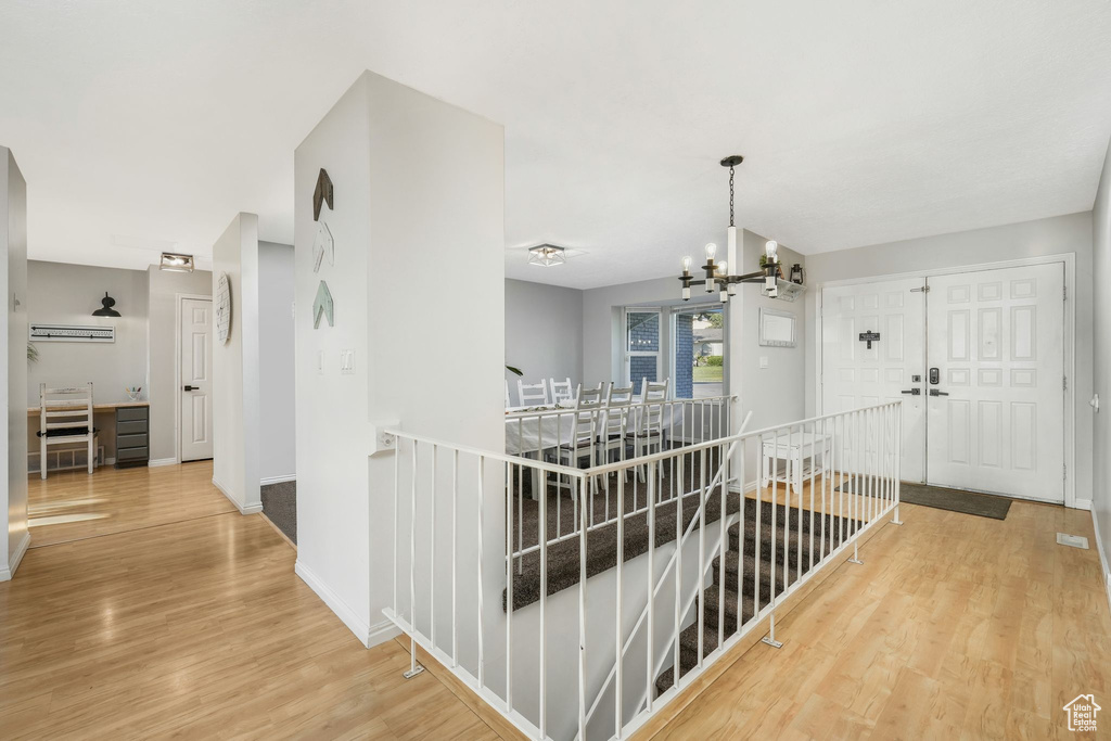 Corridor featuring an upstairs landing, wood finished floors, and a chandelier