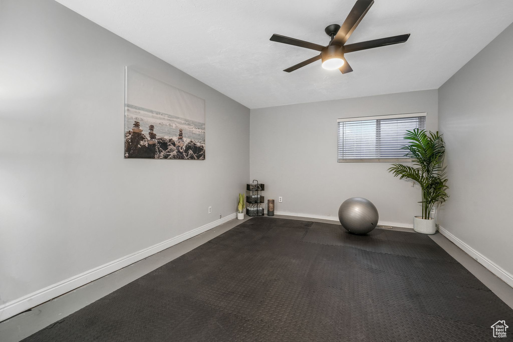 Exercise area with a ceiling fan and baseboards