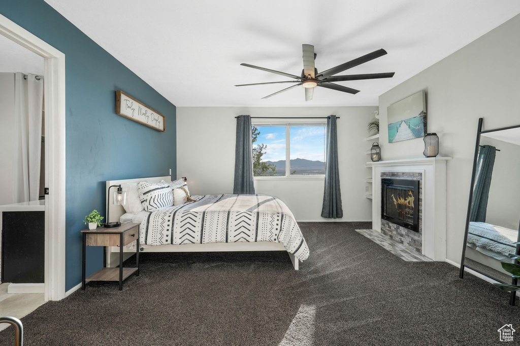 Bedroom with carpet flooring, a fireplace with flush hearth, and ceiling fan