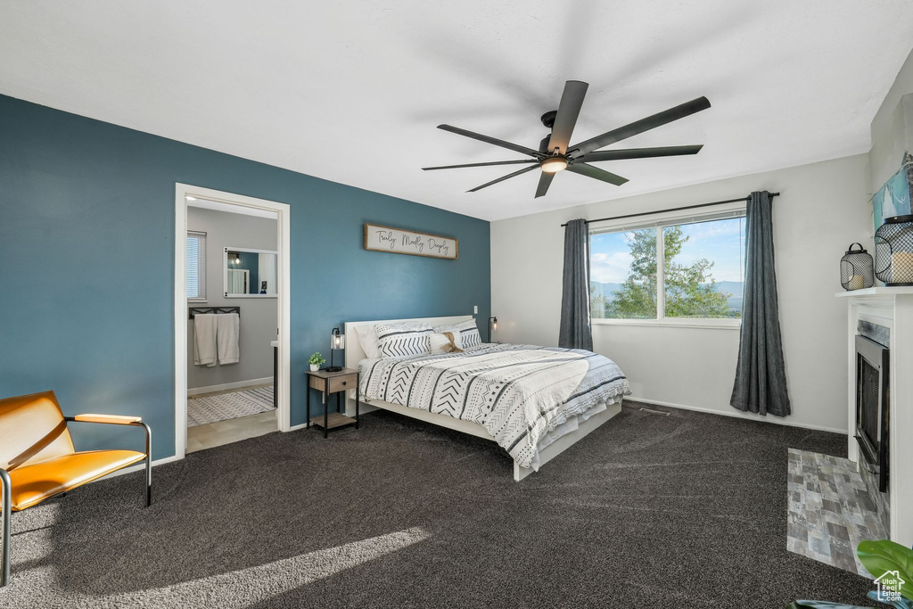 Carpeted bedroom with a fireplace with flush hearth, ceiling fan, and ensuite bathroom