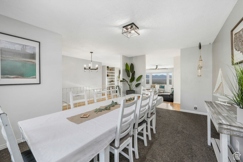 Dining room featuring dark colored carpet, a chandelier, and a ceiling fan