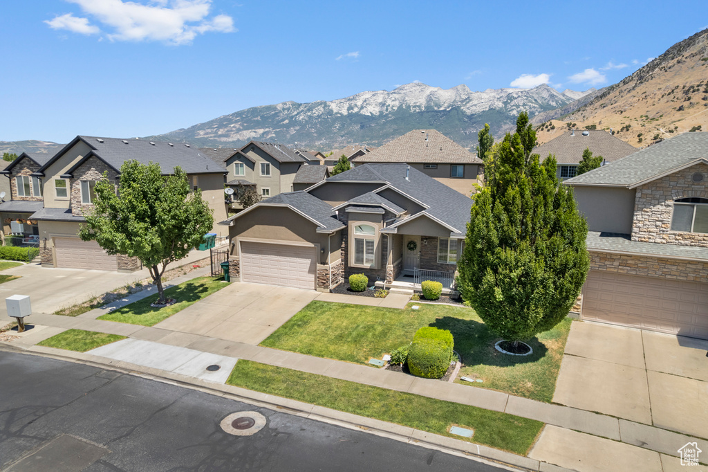 View of front facade with a residential view, driveway, stone siding, and a mountain view