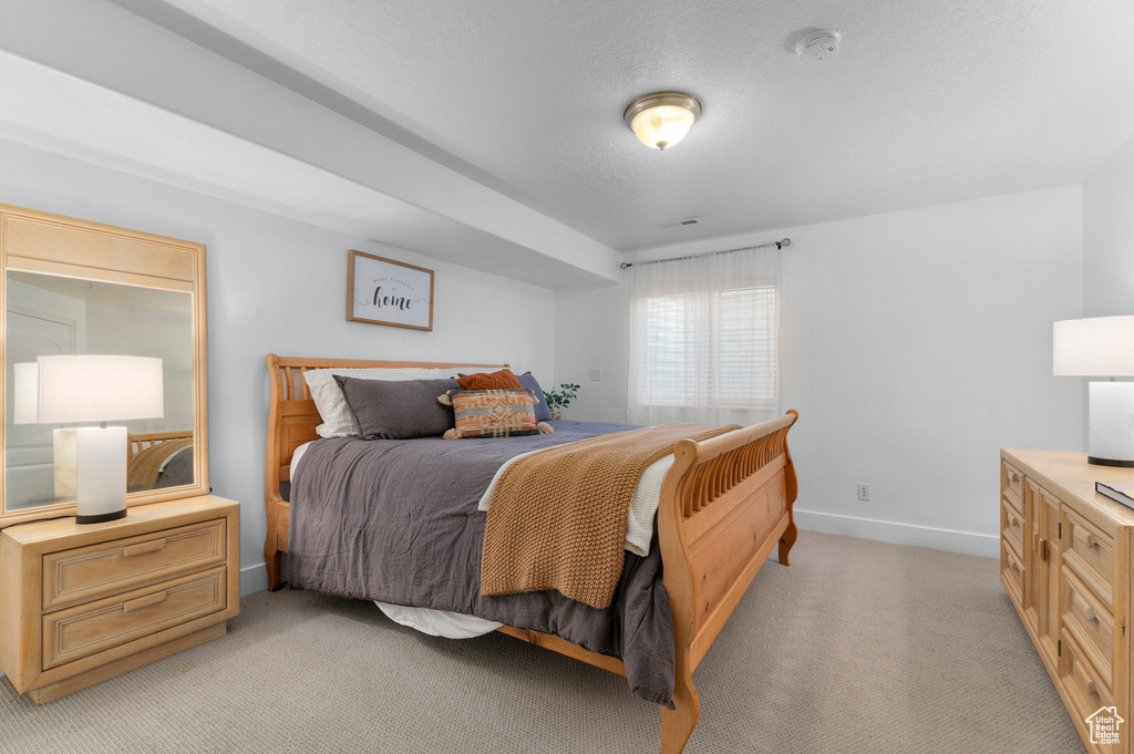 Bedroom with light colored carpet and a textured ceiling