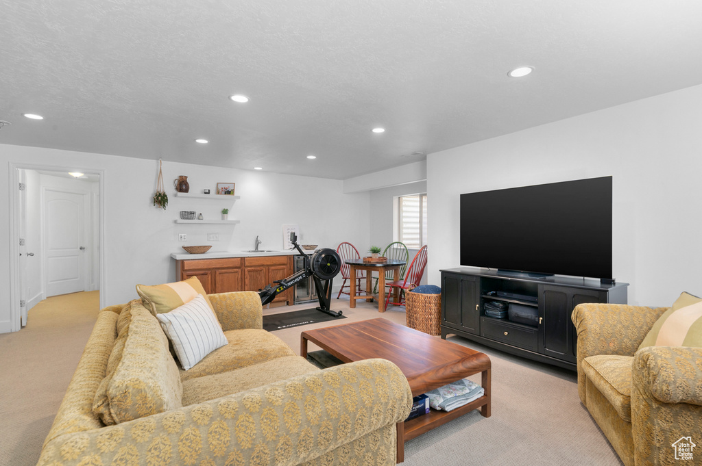Living area with light colored carpet, recessed lighting, and bar area