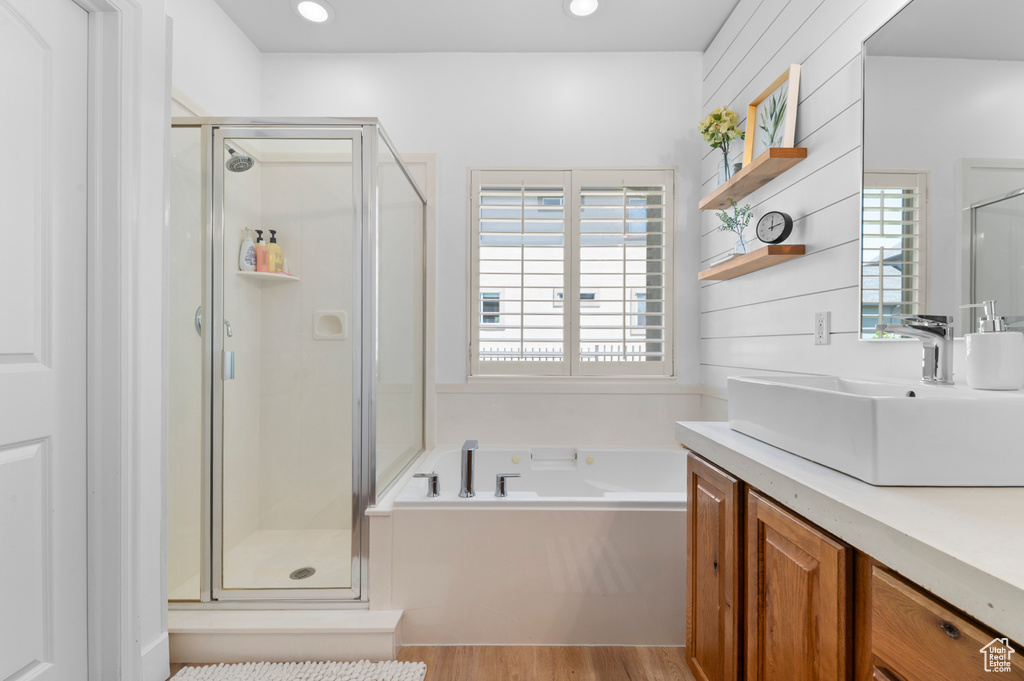 Full bath with vanity, a stall shower, a garden tub, wood finished floors, and recessed lighting