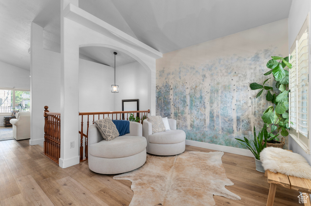Living area with wood finished floors, an upstairs landing, and high vaulted ceiling
