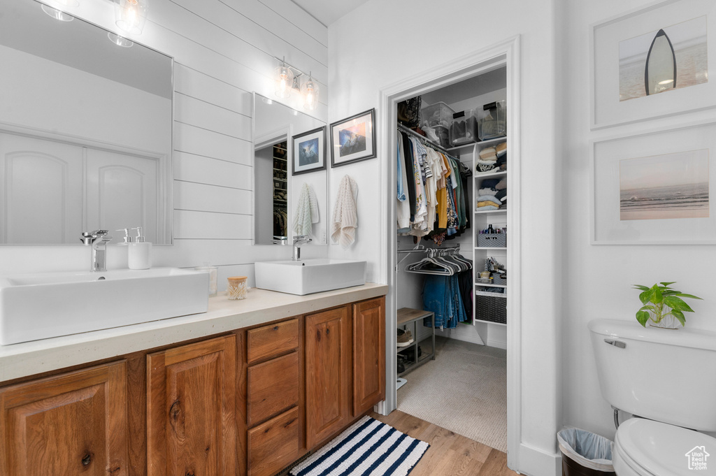 Full bath featuring double vanity, wood finished floors, and a spacious closet