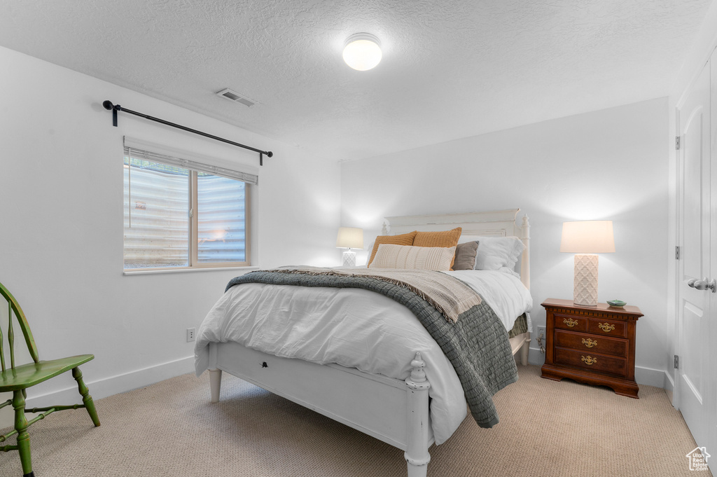 Carpeted bedroom with a textured ceiling and baseboards
