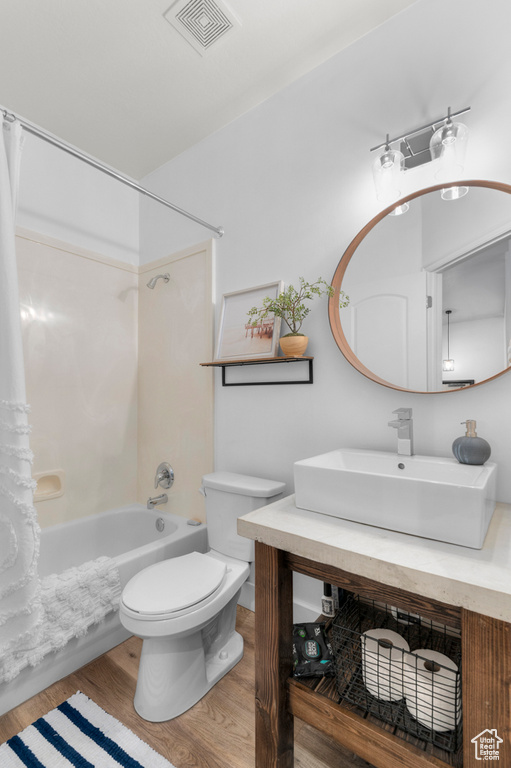 Bathroom with vanity, shower / tub combo with curtain, and wood finished floors