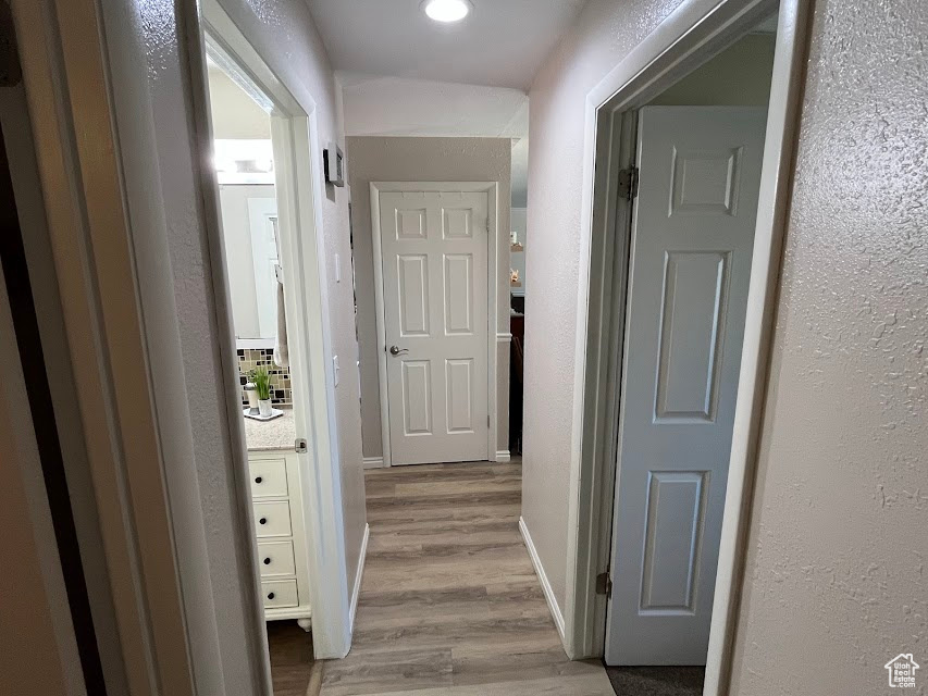 Corridor with light wood finished floors and a textured wall