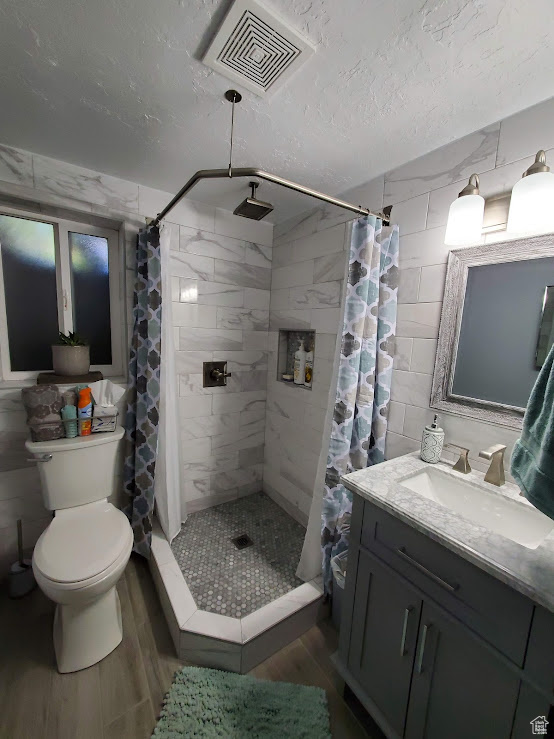 Bathroom with wood finished floors, vanity, a shower stall, and a textured ceiling