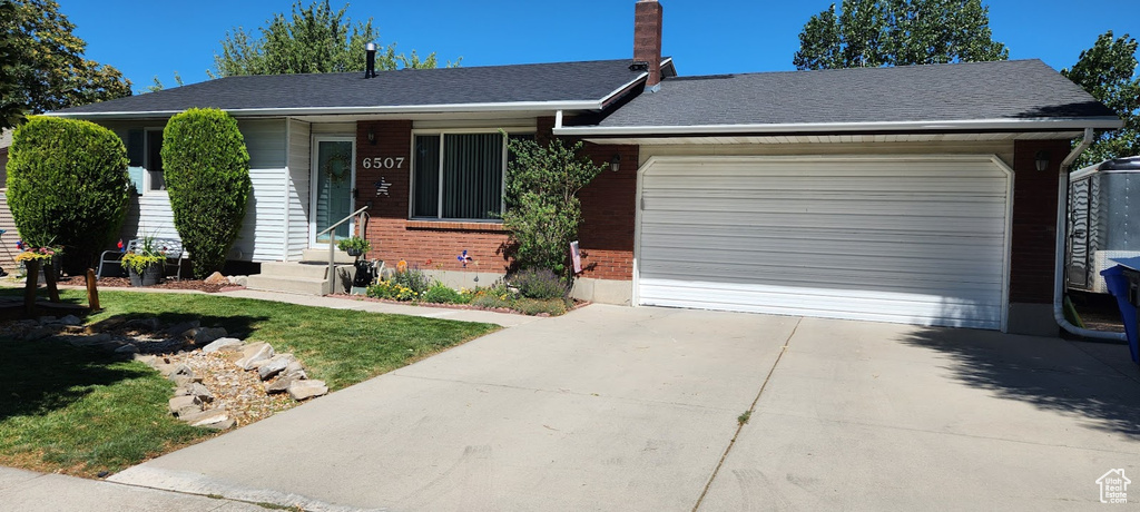 Ranch-style home with brick siding, an attached garage, driveway, and a front yard