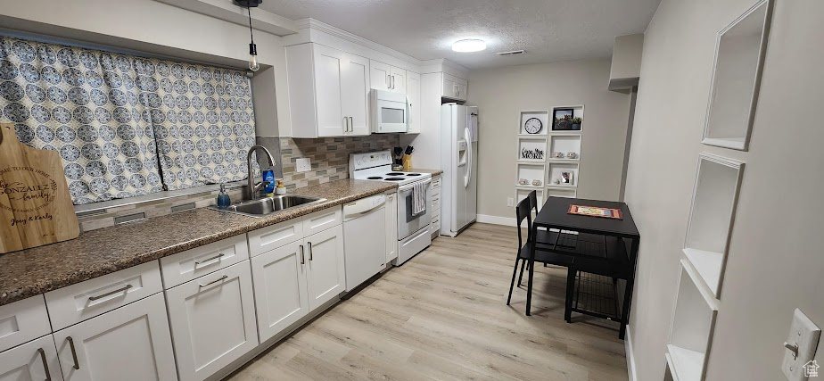 Kitchen featuring white appliances, backsplash, white cabinetry, light wood-type flooring, and a textured ceiling