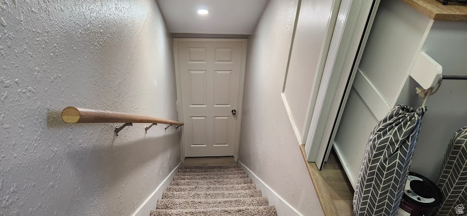 Stairs featuring a textured wall and carpet flooring