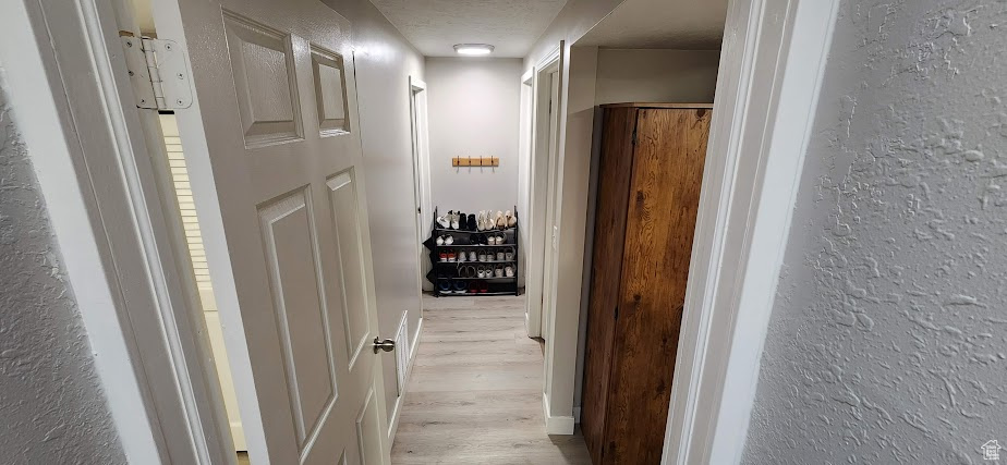Corridor with light wood-style floors and a textured wall