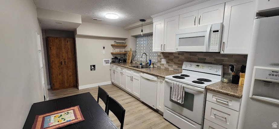 Kitchen featuring white appliances, decorative backsplash, light wood finished floors, white cabinets, and a textured ceiling