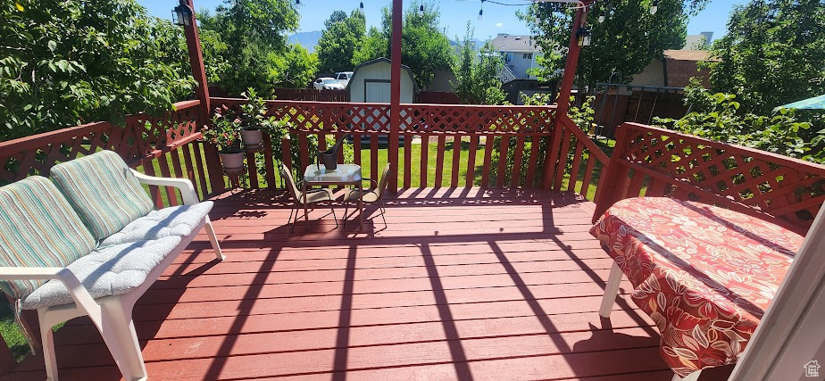 Wooden deck featuring a storage unit and a fenced backyard