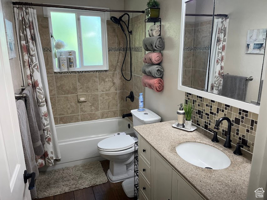 Bathroom featuring shower / bath combination with curtain, vanity, decorative backsplash, and wood finished floors