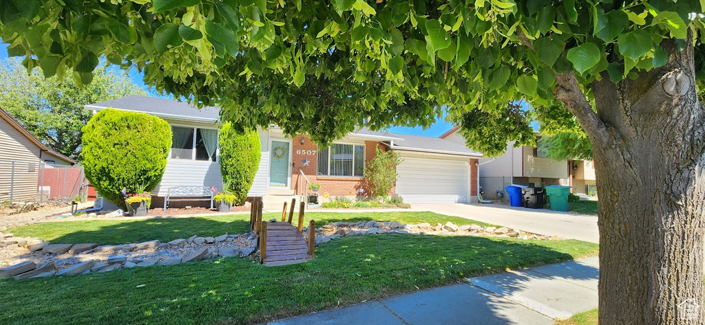 View of front of house featuring brick siding, driveway, a front yard, and a garage