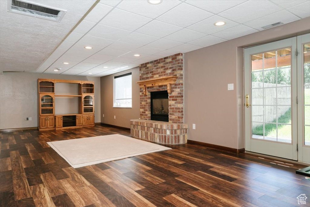 Unfurnished living room featuring dark wood finished floors, a brick fireplace, and recessed lighting