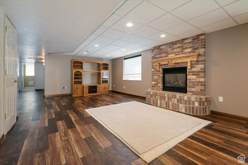 Living area with dark wood-style floors, a fireplace, plenty of natural light, recessed lighting, and a paneled ceiling