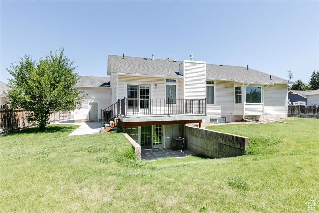 Back of house featuring a fenced backyard, a wooden deck, a chimney, a patio area, and a shingled roof