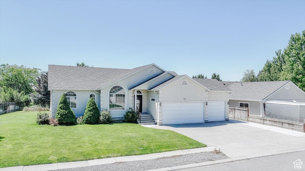 Ranch-style house with an attached garage, driveway, a shingled roof, and stucco siding