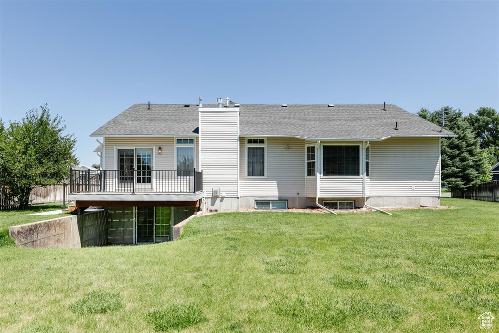 Rear view of house with a chimney, a deck, and a shingled roof