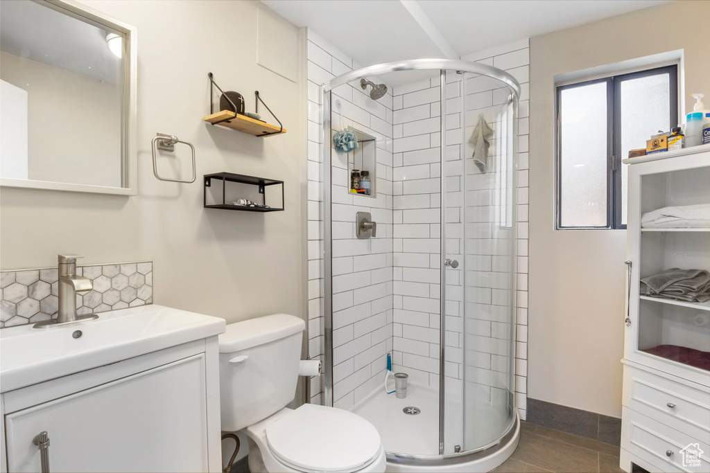 Bathroom with a stall shower, vanity, decorative backsplash, and tile patterned flooring