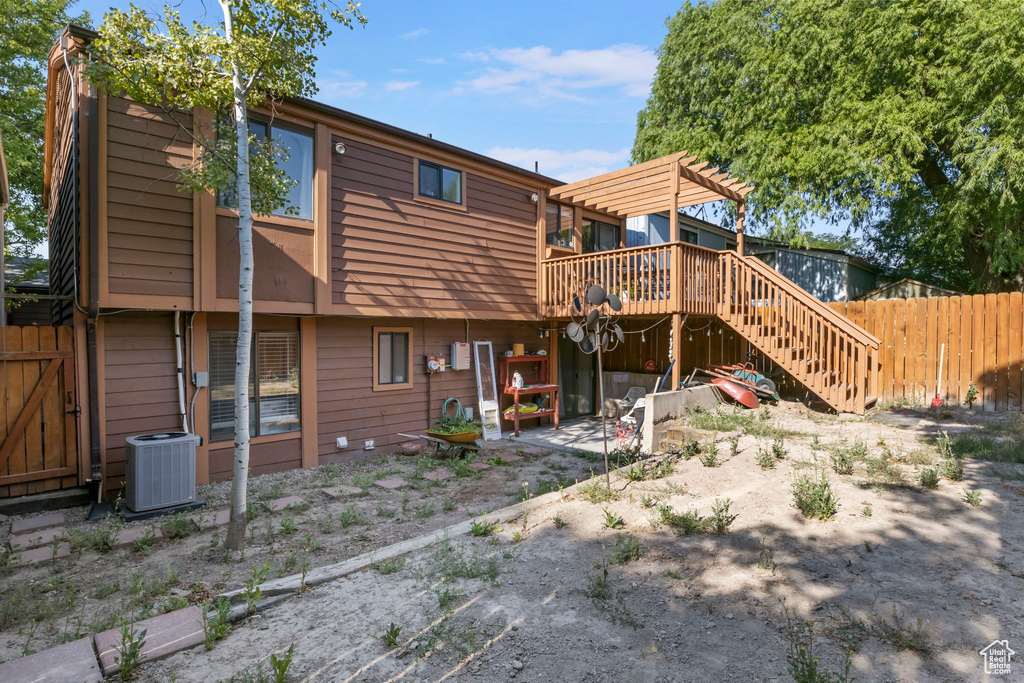 Rear view of property with a wooden deck, stairway, and a pergola