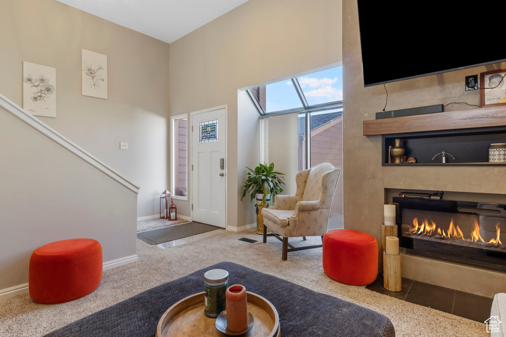 Living room featuring carpet floors, a glass covered fireplace, and a skylight