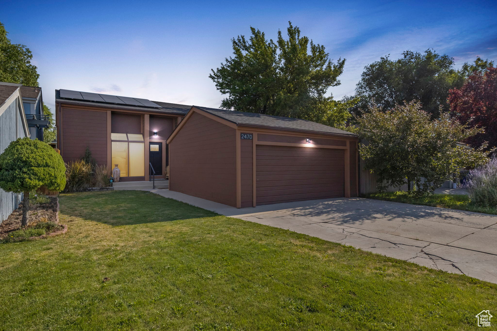 View of front of house with solar panels, a yard, and driveway