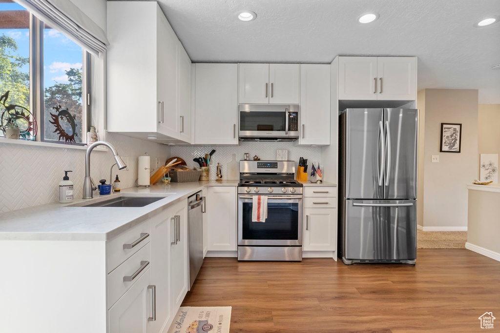 Kitchen with appliances with stainless steel finishes, white cabinetry, decorative backsplash, and recessed lighting