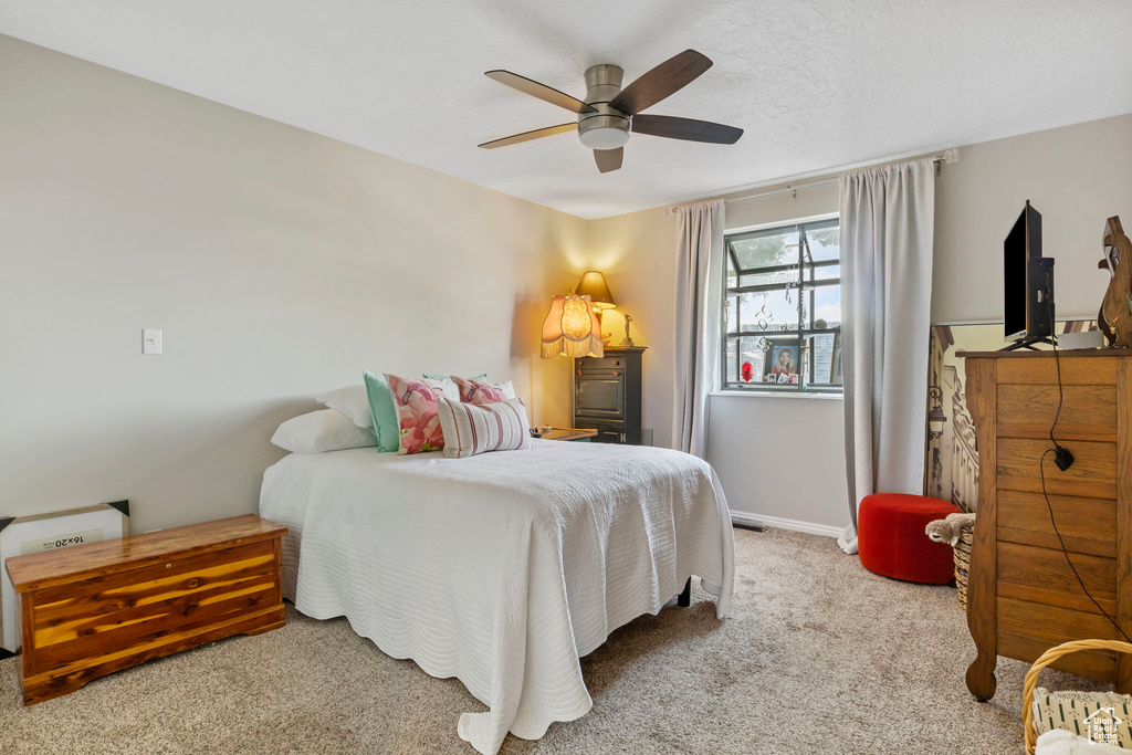 Carpeted bedroom featuring ceiling fan and baseboards
