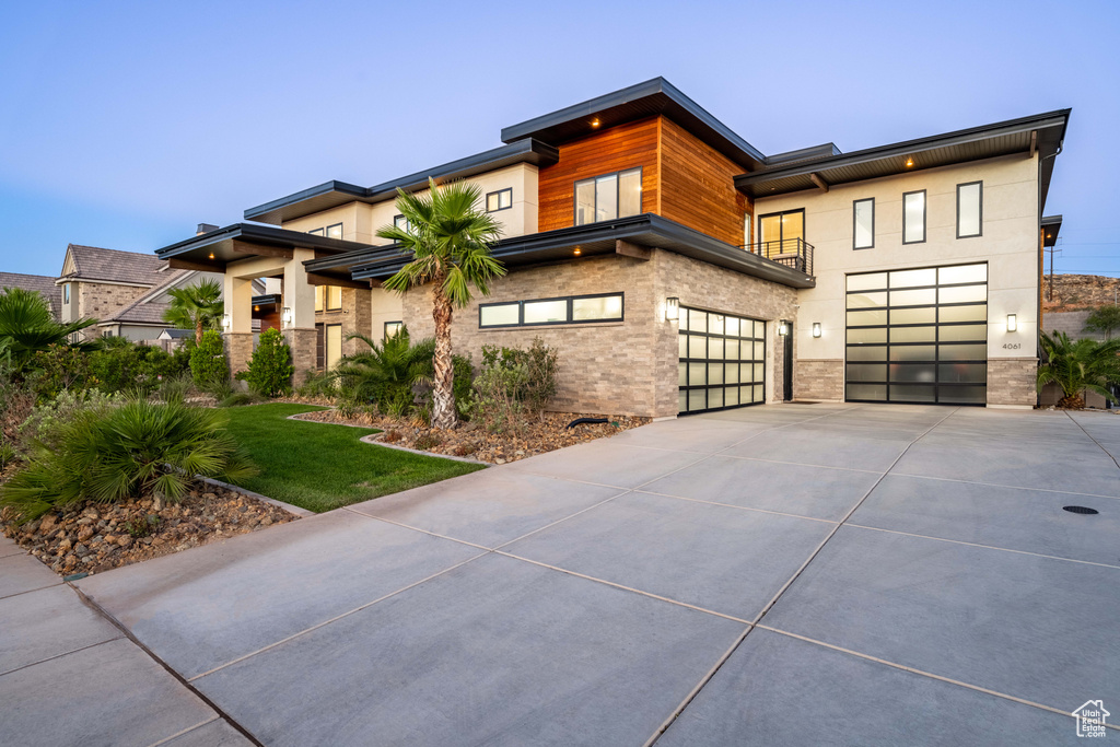 Contemporary home with concrete driveway, an attached garage, and a front lawn