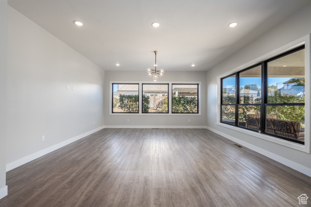 Empty room featuring a chandelier, recessed lighting, and dark wood finished floors