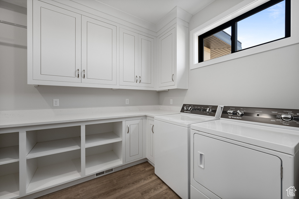 Washroom with washer and clothes dryer, cabinet space, and dark wood-style flooring