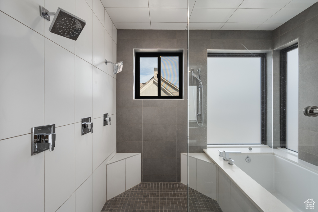 Full bath featuring tiled shower, a garden tub, and tile walls