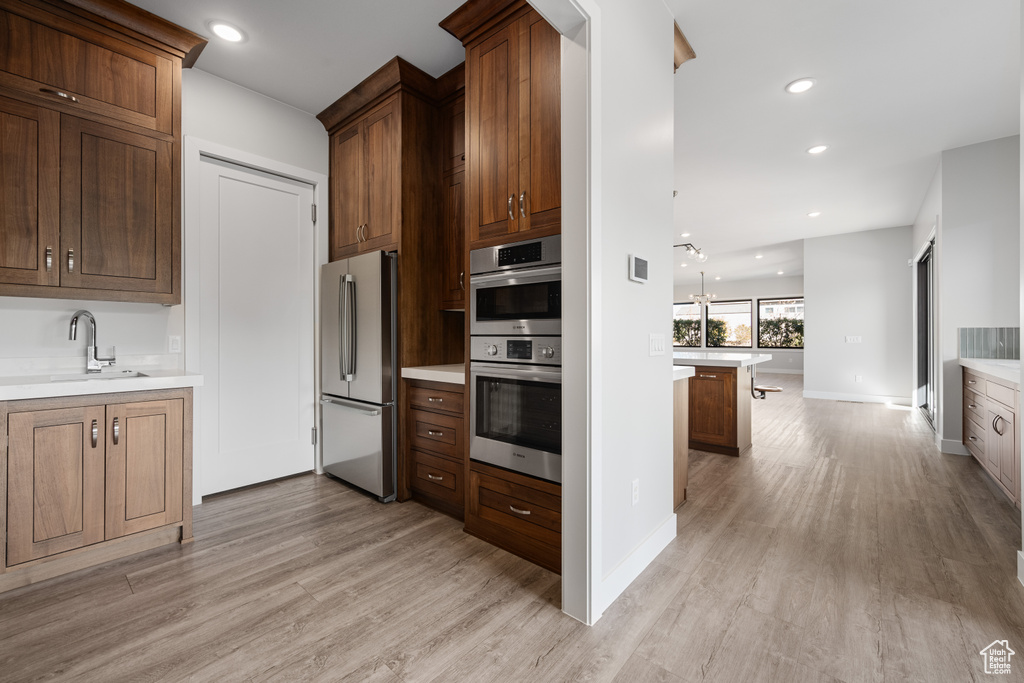 Kitchen featuring stainless steel appliances, light wood-type flooring, light countertops, and recessed lighting