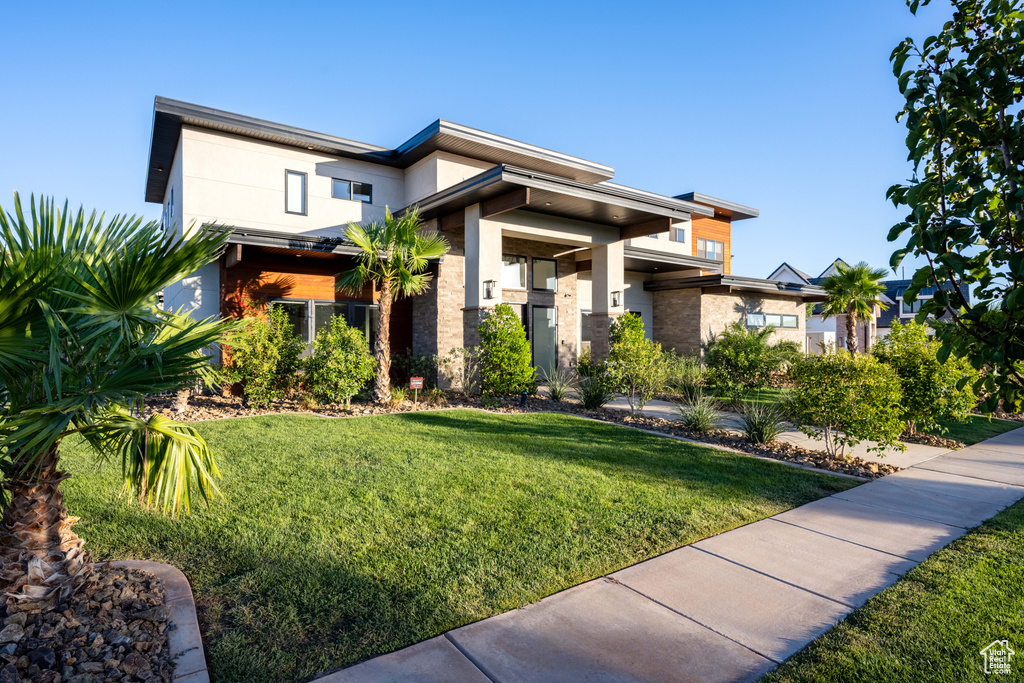 View of front of property with a front yard, stucco siding, and brick siding