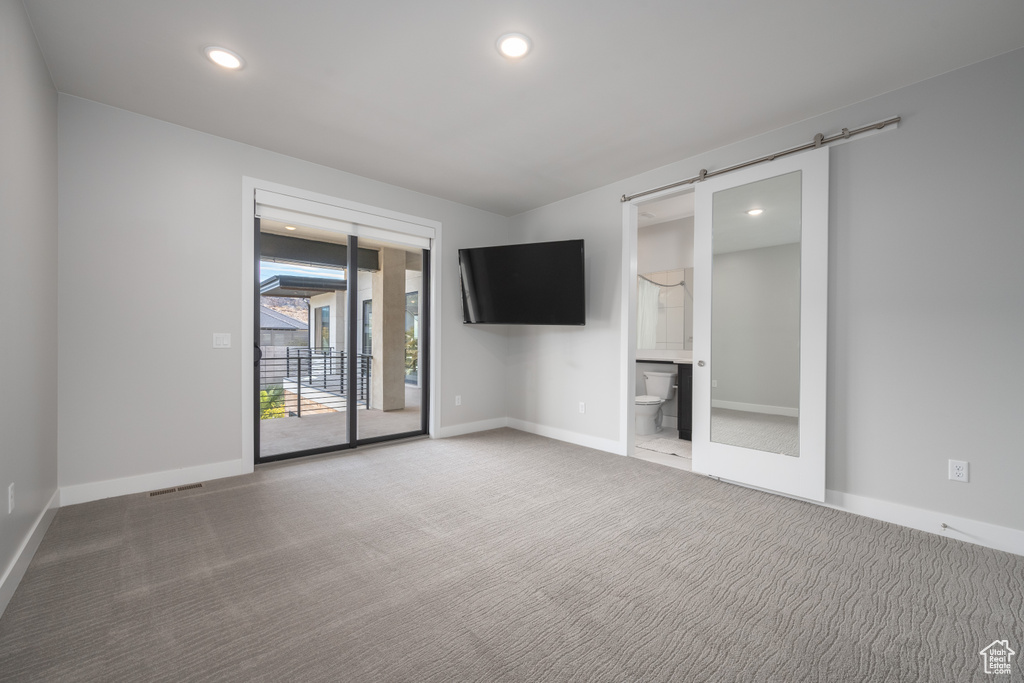 Carpeted empty room with recessed lighting and a barn door